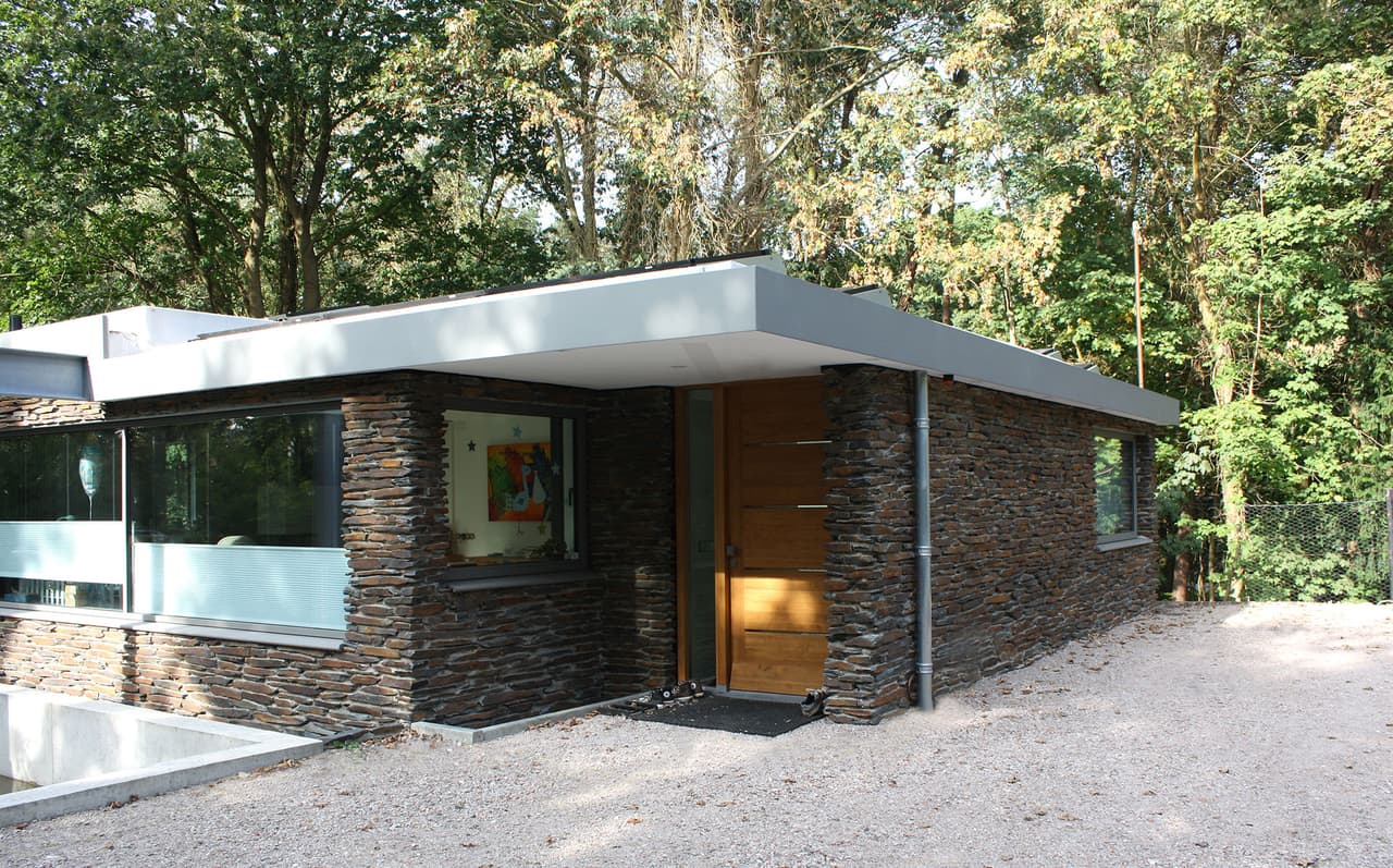 Entree van de bungalow met overstekend dak en gevel van leisteen