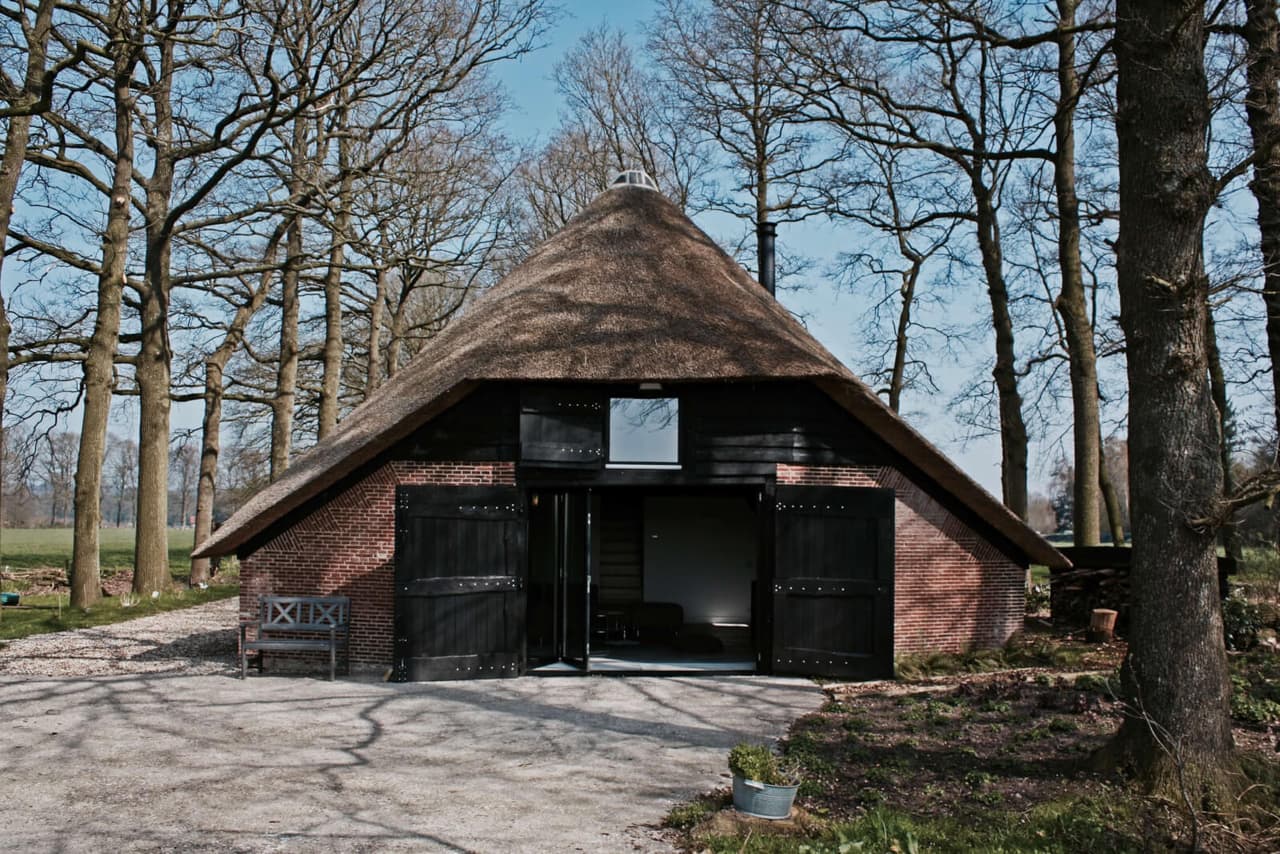 Schaapskooi met rieten kap tussen de eiken van landgoed Sandenburg