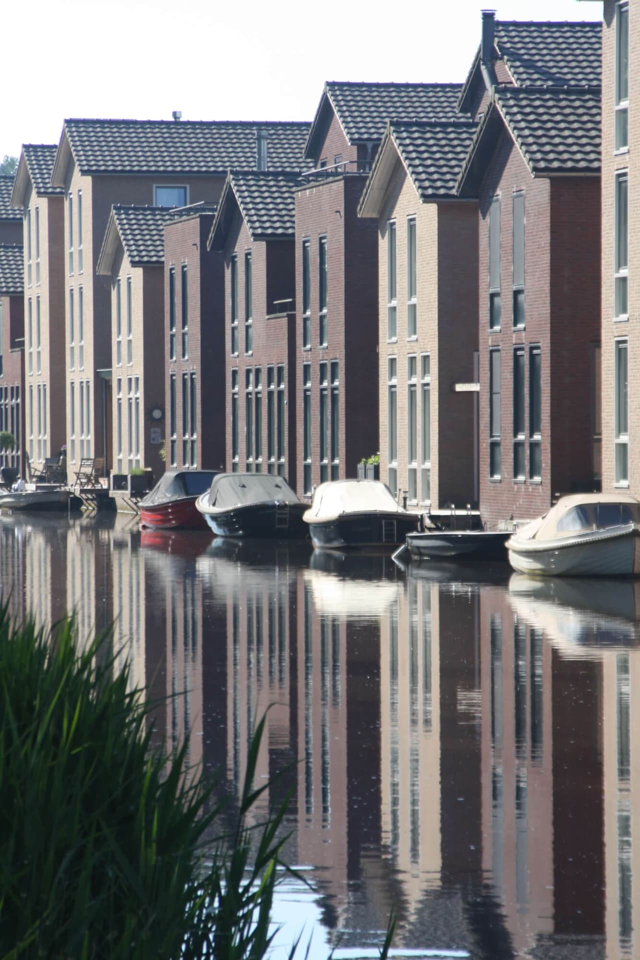 Bakstenen woningen aan de Laak die zich spiegelen in het water